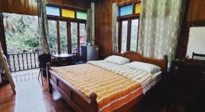a bedroom with a bed in a room with windows at River Jam Amphawa in Amphawa