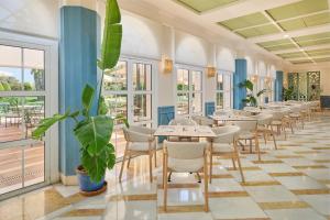a row of tables and chairs in a room with windows at Grupotel Playa Club in Son Xoriguer