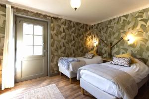 a bedroom with two beds and a window and a door at Uylenburg- Du Midi in Delft