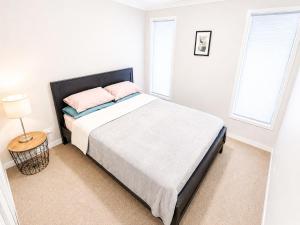 a white bedroom with a large bed with pink pillows at 4 Bedrooms Home in Gledswood Hills
