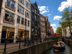 a boat on a canal in a city with buildings at De Herbert Amsterdam - Formerly France Hotel in Amsterdam