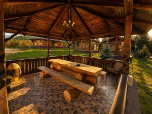 a wooden table and bench under a wooden pavilion at Casa Dragomir in Plaiu Şarului