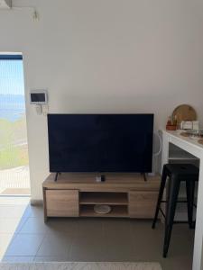 a flat screen tv sitting on top of a wooden entertainment center at Calmora by the Sea in Ancient Epidauros