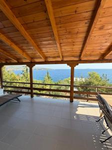 a wooden roof with chairs on a porch with the ocean in the background at Calmora by the Sea in Ancient Epidauros