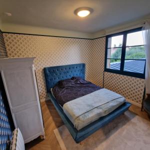 a bedroom with a blue bed and a window at Le Ratna in Groslay