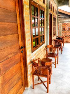 a row of wooden chairs and tables on a porch at Kaliele House in Domine Eduard Osok Airport