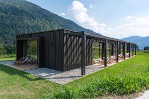 a black building with a group of chairs in a field at Agriturismo Maso Loera in Pelugo