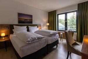 a hotel room with a bed and a desk and window at Seehotel Berlin-Rangsdorf in Rangsdorf