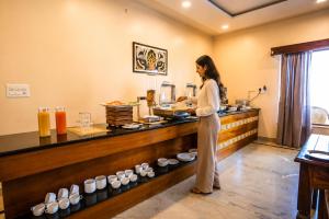 a woman standing in front of a counter with food at RajBagh by Aaryam in Sawāi Mādhopur +36 photos