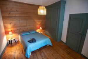 a bedroom with a bed with a wooden wall at L'échappée Jurassienne - Tout équipé au calme in Saint-Claude