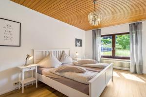 a bedroom with a large bed and a chandelier at Fewo Wrede am Sauerland-Radring 1 in Wenholthausen