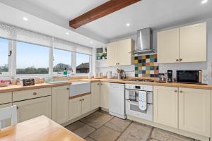 a large kitchen with white cabinets and windows at Traditional Cotswold escape with garden and fireplace in Cheltenham +20 photos