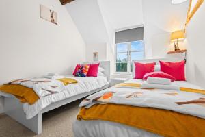 two beds in a white room with red pillows at Traditional Cotswold escape with garden and fireplace in Cheltenham