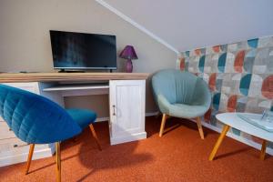a room with a desk with a tv and two chairs at Penzión Aira in Zvolen