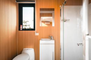 a bathroom with a white toilet and a window at Raya and Aiden Farm House by Tiny Away in Cooma