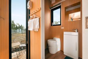 a bathroom with a toilet and a window at Raya and Aiden Farm House by Tiny Away in Cooma
