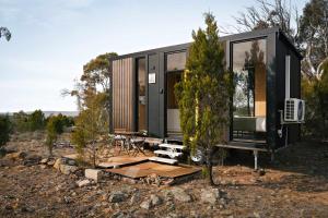 a black tiny house with a wooden deck at Raya and Aiden Farm House by Tiny Away in Cooma