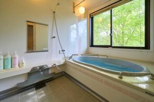 a bath tub in a bathroom with a window at Suite Villa Panora Yatsugatake in Minamimaki +53 photos