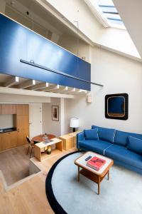a living room with a blue couch and a table at Faubourg 21 - The Leading Hotels of the World in Brussels