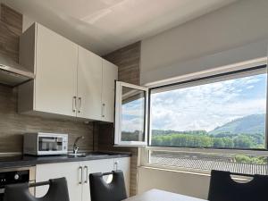 a kitchen with a microwave and a large window at Alojamiento Picos de Europa VUT-2458-AS in Arriondas