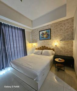 a bedroom with a large white bed and a table at Modern studio with a stûnning view at 32 floor in Jakarta +6 photos