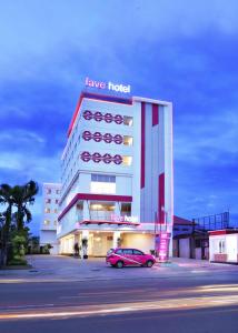 favehotel Olo Padang في بادانج: سيارة وردية متوقفة أمام مبنى