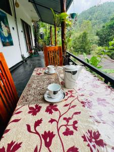 a table with a table cloth with two cups on it at Ella Hermitage View in Ella