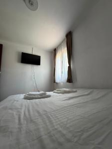 a bedroom with a bed with white sheets and a window at Colț de Vâlsan in Brăduleţ