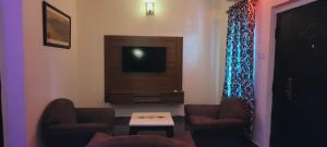 a living room with two chairs and a television at Optizee Hotel and Suites in Agege
