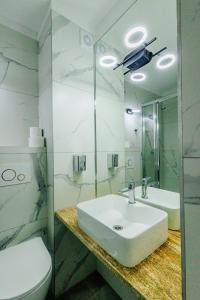 a bathroom with a sink and a toilet and a mirror at Parkova - pokoje hotelowe in Gołdap +28 photos
