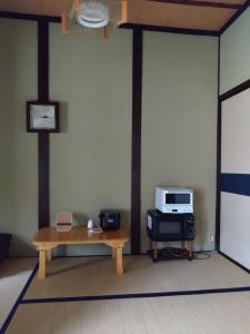 a living room with a table and a microwave at ゲストハウスぬっく in Tanabe
