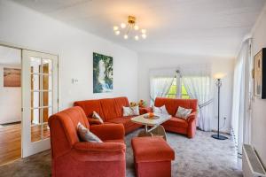 a living room with two orange chairs and a table at Ferienhaus Rauchfangswerder in Berlin