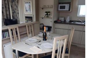 a dining room table with a bottle of wine on it at 3-Bed Caravan Sleeps 7 with Indoor Pool in Wigton