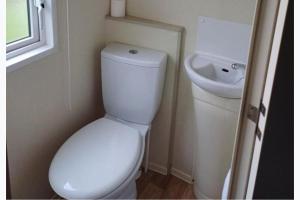 a bathroom with a white toilet and a sink at 3-Bed Caravan Sleeps 7 with Indoor Pool in Wigton +7 photos