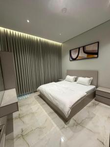 a bedroom with a white bed and a large window at خالد للشقق in Ar Rass