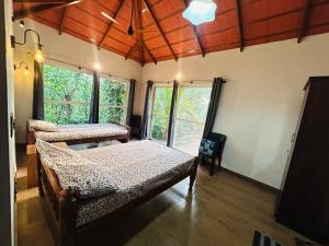 a bedroom with two beds in a room with windows at Janapriya Villa 2 in Mudigere