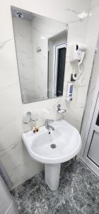 a white bathroom with a sink and a mirror at Registan Stay in Samarkand