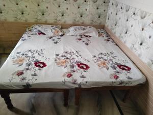 a bed with a white comforter with flowers on it at Harekrishna Nilayam in Vemalwāda