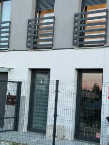 a white building with windows and a fence at Apartament Venis ul Jodłowa in Opole