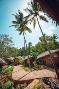 a path leading to a resort with palm trees at SAMA The Silver Creek in Bogmalo