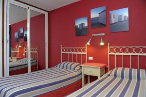 a bedroom with two beds and a red wall at Apartamentos Miriam in Puerto Rico de Gran Canaria