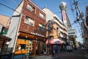 um edifício numa rua com uma torre ao fundo em The Pax Hostel em Osaka