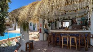 a bar under a straw umbrella next to a swimming pool at Casa Bambú Boutique Studios Andalusië with pool and Mountain Views in Vélez-Málaga