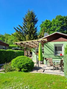 a green house with a table and a umbrella at Ferienhaus Hilde in Sangerhausen
