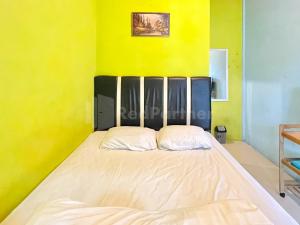 a bedroom with a large bed with yellow walls at Penginapan Gindo Sidebuk Debuk Berastagi RedPartner in Berastagi