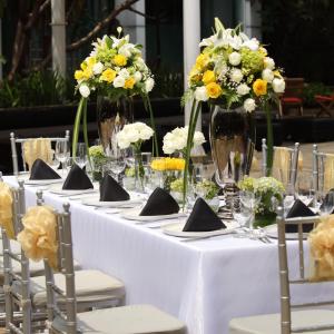 a long white table with vases of flowers on it at Grandkemang Hotel in Jakarta