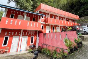 a red building with cars parked in front of it at Penginapan Gindo Sidebuk Debuk Berastagi RedPartner in Berastagi