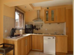 a kitchen with wooden cabinets and a white refrigerator at Cottage in Aywaille with Garden in Aywaille