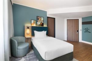 a bedroom with a bed and a chair at Spark by Hilton Essen City Centre in Essen +69 photos