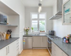 a white kitchen with a sink and a window at Harrison House in Featherston